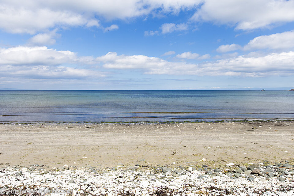 Blauer Himmel und Wolken über dem Strand beim Ballygalley Castle